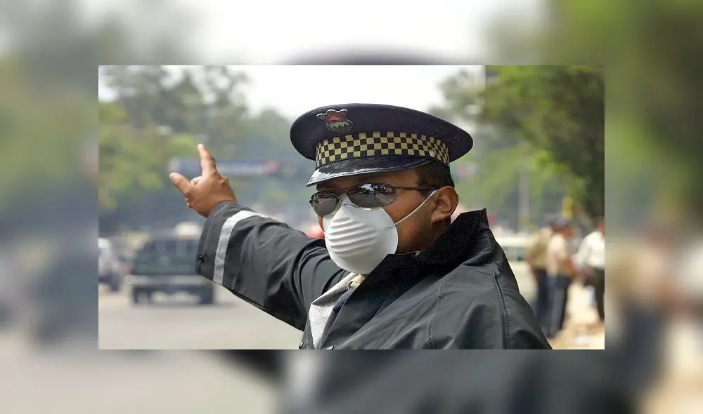 Erick Naz, un oficial de la Polic�a de Tr�nsito dirige el tr�fico vehicular en ciudad de Guatemala, mientras se proteje con una mascarilla las v�as respiratorias. La capital, una ciudad de casi tres millones de habitantes es una de las metr�polis m�s contaminadas del �rea centroamericana.    AFP  PHOTO/Orlando SIERRA. (Photo by ORLANDO SIERRA / AFP)