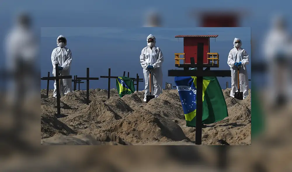 Activistas de la ONG brasileña Río de Paz parados junto a 100 tumbas simbólicas en la playa de Copacabana. | Foto: Carl de Souza / AFP