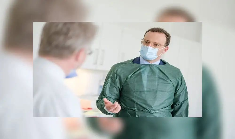 German Health Minister Jens Spahn (R) wears a face mask as he speaks with Christoph Schindler, clinical researcher at the Clinicial Research Center (CRC) of the Medizinische Hochschule Hannover (MHH) medical university, during a visit at the centre's department for research on primary vaccination, on April 28, 2020 in Hanover, northern Germany. (Photo by Ole Spata / POOL / AFP)