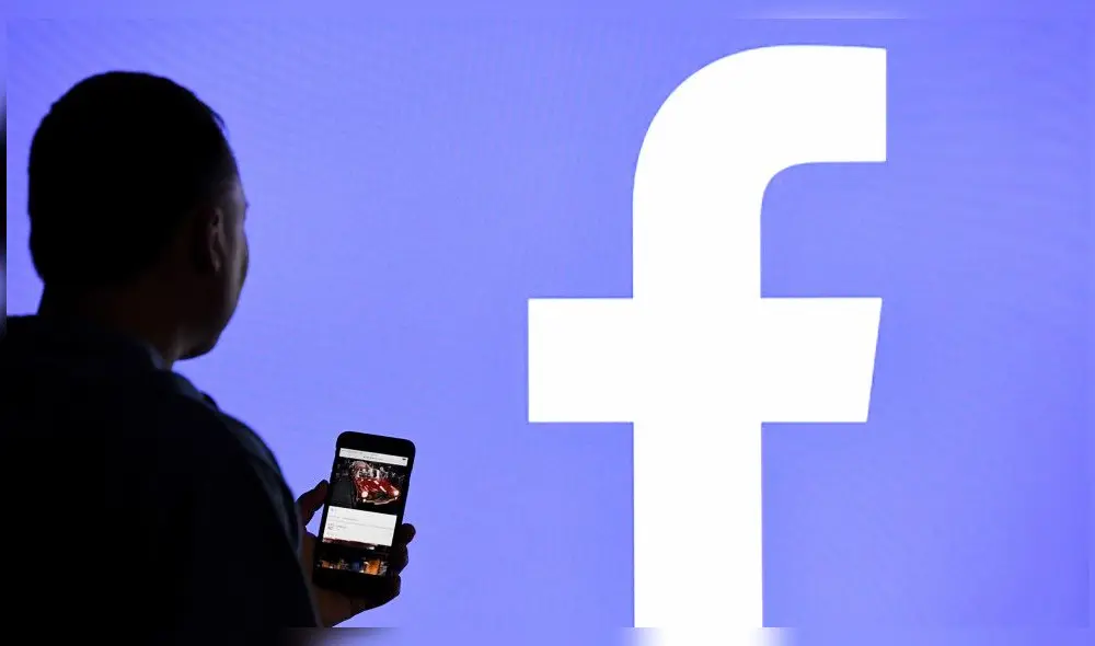 15 March 2019, Schleswig-Holstein, Aukrug-Homfeld: ILLUSTRATION - A man with a smartphone stands in front of a monitor with the Facebook logo. (Credit Image: © Carsten Rehder/DPA via ZUMA Press)