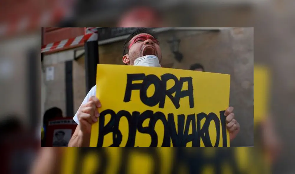 Un ciudadano de Brasil sostiene una pancarta en protesta contra Jair Bolsonaro. Foto: Oscar del Pozo/AFP.