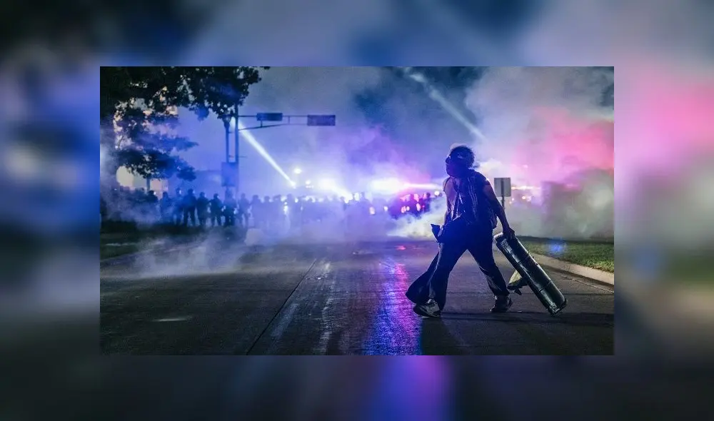 KENOSHA, WI - AUGUST 25: A demonstrator carries a make-shift shield across the street on August 25, 2020 in Kenosha, Wisconsin. As the city declared a state of emergency curfew, a third night of civil unrest occurred after the shooting of Jacob Blake, 29, on August 23. Video shot of the incident appears to show Blake shot multiple times in the back by Wisconsin police officers while attempting to enter the drivers side of a vehicle. The 29-year-old Blake was undergoing surgery for a severed spinal cord, shattered vertebrae and severe damage to organs, according to the family attorneys in published accounts.   Brandon Bell/Getty Images/AFP