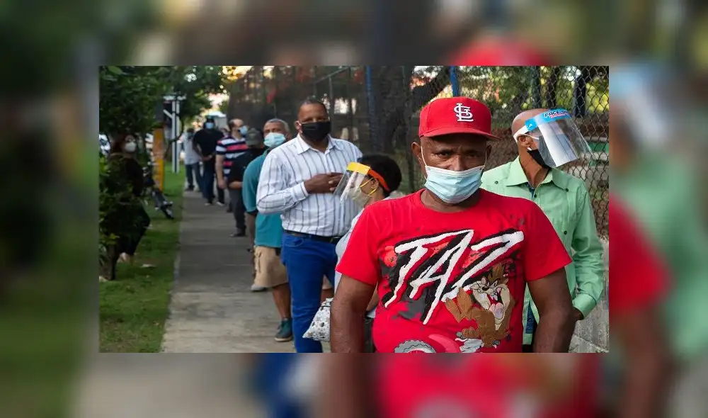 People queue to vote at a polling station during General Elections in Santo Domingo, on July 5, 2020 amid the COVID-19 coronavirus pandemic. - Voters in the Dominican Republic are set to defy rising coronavirus infections on Sunday to choose a new president in an election that could end 16 years of unbroken rule by the center-left Dominican Liberation Party. (Photo by STR / AFP)