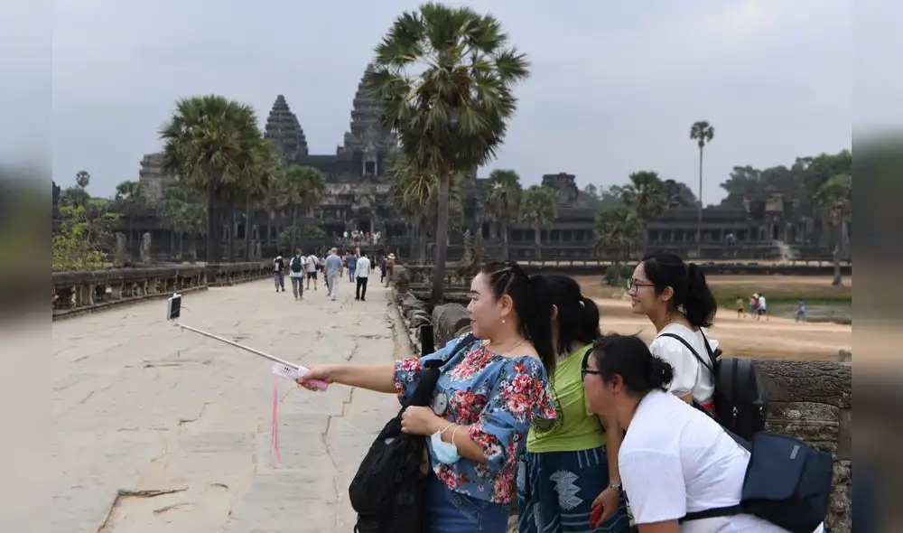 Tourists pose for a selfie during their visit to the Angkor Wat temple in Siem Reap province on March 6, 2020. - The deadly COVID-19 novel coronavirus epidemic will cost world tourism at least $22 billion owing to a drop in spending by Chinese tourists, the head of the World Travel and Tourism Council said on February 27. (Photo by TANG CHHIN Sothy / AFP) Tourists pose for a selfie during their visit to the Angkor Wat temple in Siem Reap province on March 6, 2020. - The deadly COVID-19 novel coronavirus epidemic will cost world tourism at least $22 billion owing to a drop in spending by Chinese tourists, the head of the World Travel and Tourism Council said on February 27. (Photo by TANG CHHIN Sothy / AFP)