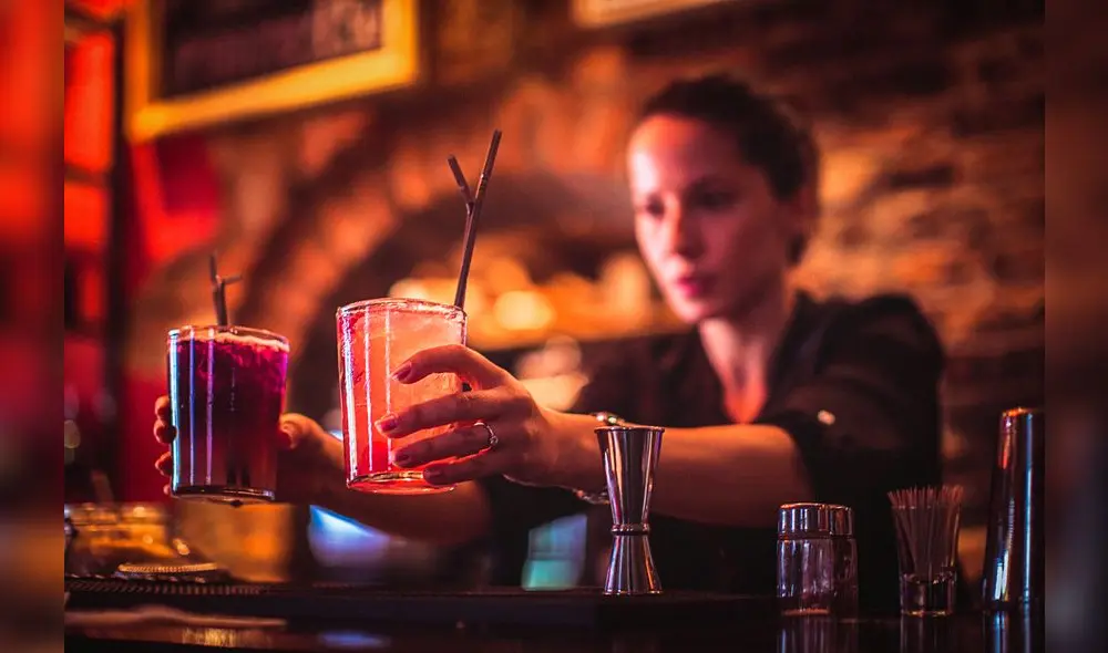 Close-up of a young female bartender serving cocktails in a nightlife cocktail bar. Selective focus. Focus on foreground. Close-up of a young female bartender serving cocktails in a nightlife cocktail bar. Selective focus. Focus on foreground.