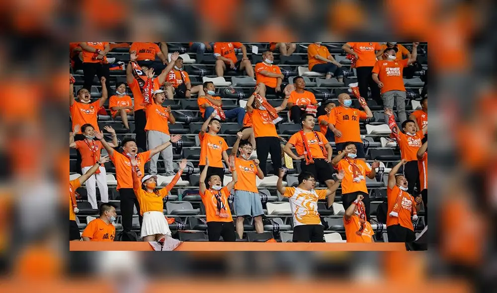 Con el color naranja del equipo y algunos sin mascarilla festejaron el regreso de la hinchada al estadio de Wuhan, donde surgió el coronavirus. Foto: AFP Con el color naranja del equipo y algunos sin mascarilla festejaron el regreso de la hinchada al estadio de Wuhan, donde surgió el coronavirus. Foto: AFP