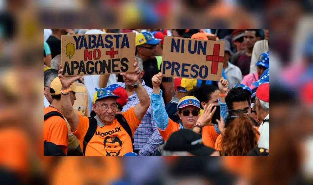 La gente sostiene carteles que decían "Basta de apagones" y "Ni un prisionero más" antes de una sesión de la Asamblea Nacional liderada por la oposición en la plaza Alfredo Sadel en Caracas el 23 de julio de 2019. Foto: AFP. La gente sostiene carteles que decían "Basta de apagones" y "Ni un prisionero más" antes de una sesión de la Asamblea Nacional liderada por la oposición en la plaza Alfredo Sadel en Caracas el 23 de julio de 2019. Foto: AFP.
