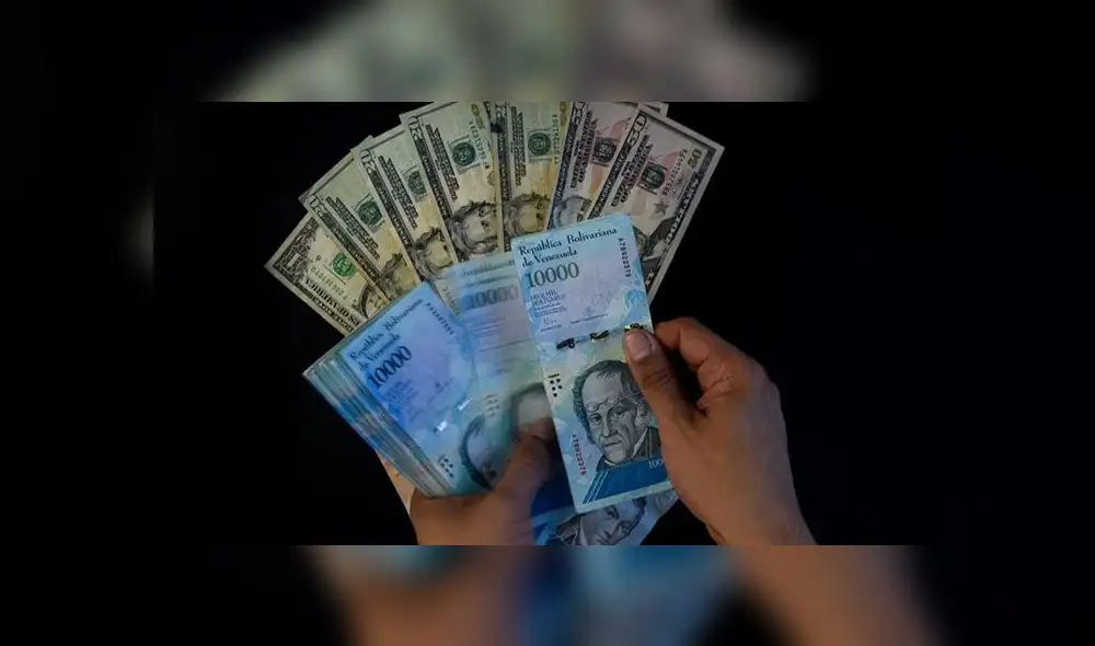 A man counts Venezuelan bolivar banknotes next to US dollar bills in Caracas on August 2, 2018. - Venezuela's government on Thursday loosened the tight currency controls it first put in place 15 years ago, with the pro-government Constituent Assembly announcing the passage of a decree authorizing money exchange operations. (Photo by Federico PARRA / AFP)