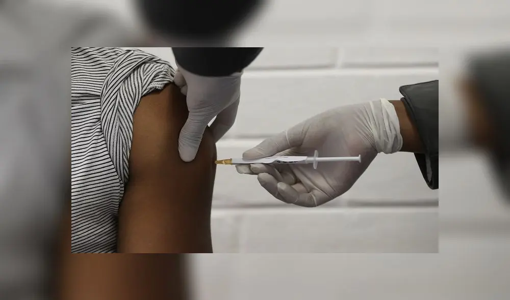 One of the first South African Oxford vaccine trialists looks on as a medical worker injects him with the clinical trial for a potential vaccine against the COVID-19 coronavirus at the Baragwanath hospital in Soweto, South Africa, on June 24 ,2020. (Photo by SIPHIWE SIBEKO / POOL / AFP)