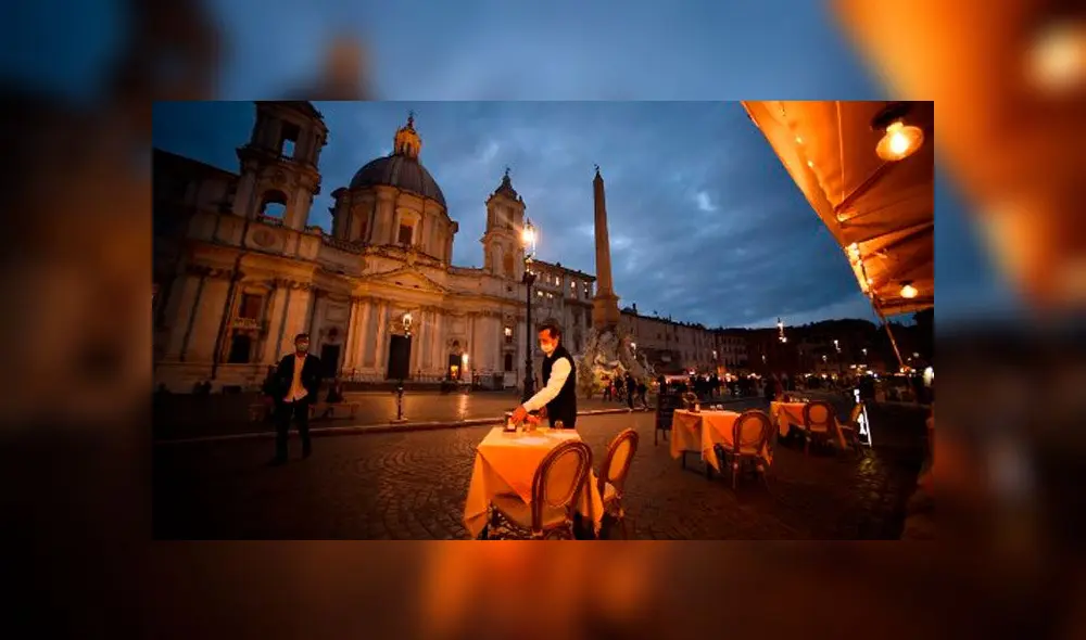 Un empleado limpia una mesa en una terraza vacía en la plaza Piazza Navona en Roma el 23 de octubre de 2020. Foto: AFP