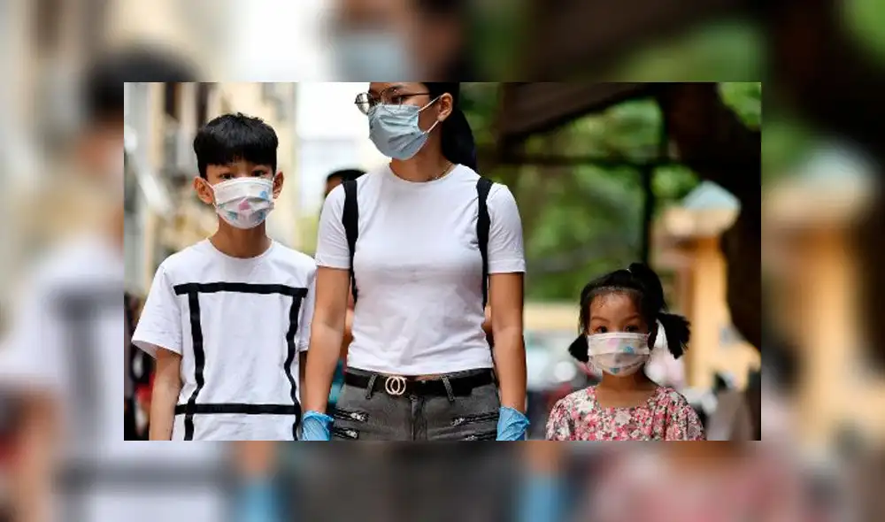 Madre e hijo caminan por la calle cubriendo su rostros para evitar el contagio. Foto: AFP. Madre e hijo caminan por la calle cubriendo su rostros para evitar el contagio. Foto: AFP.
