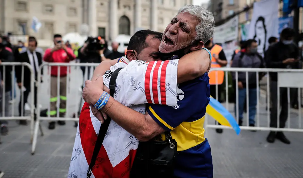 En los exteriores de la Casa Rosada, dos hinchas de River Plate y Boca Juniors dejaron de lado la rivalidad y se fundieron en un abrazo por Maradona. Foto: EFE
