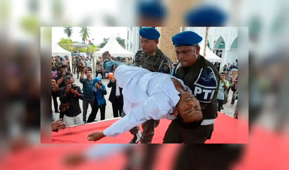Policías cargan a hombre que se desmayó mientras lo azotaban. Foto: AFP Policías cargan a hombre que se desmayó mientras lo azotaban. Foto: AFP