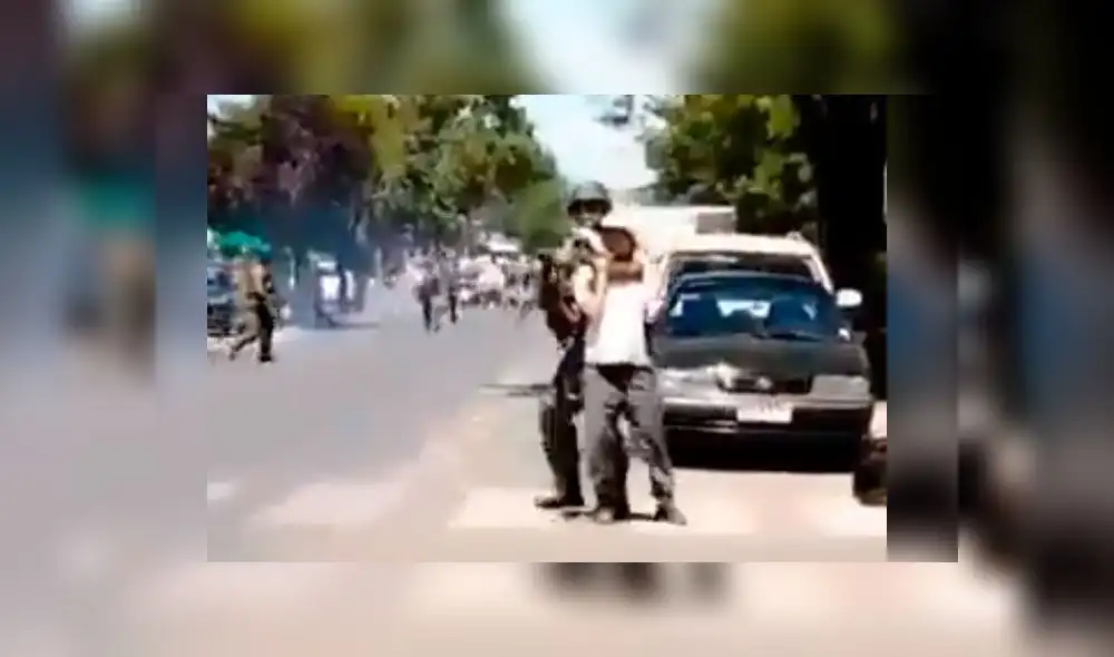 El carabinero usó al presunto menor de 13 años para cubrirse mientras disparaba a los manifestantes. Captura de video. El carabinero usó al presunto menor de 13 años para cubrirse mientras disparaba a los manifestantes. Captura de video.