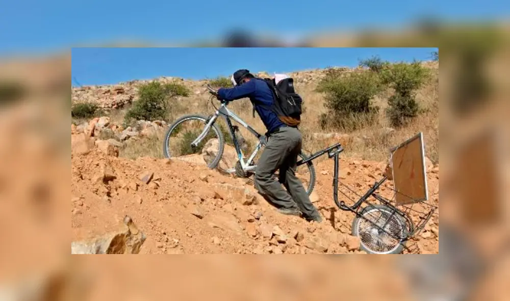 Wilfredo Negrete recorre el campo montado en su bicicleta y con una pizarra a cuestas. Foto: AFP