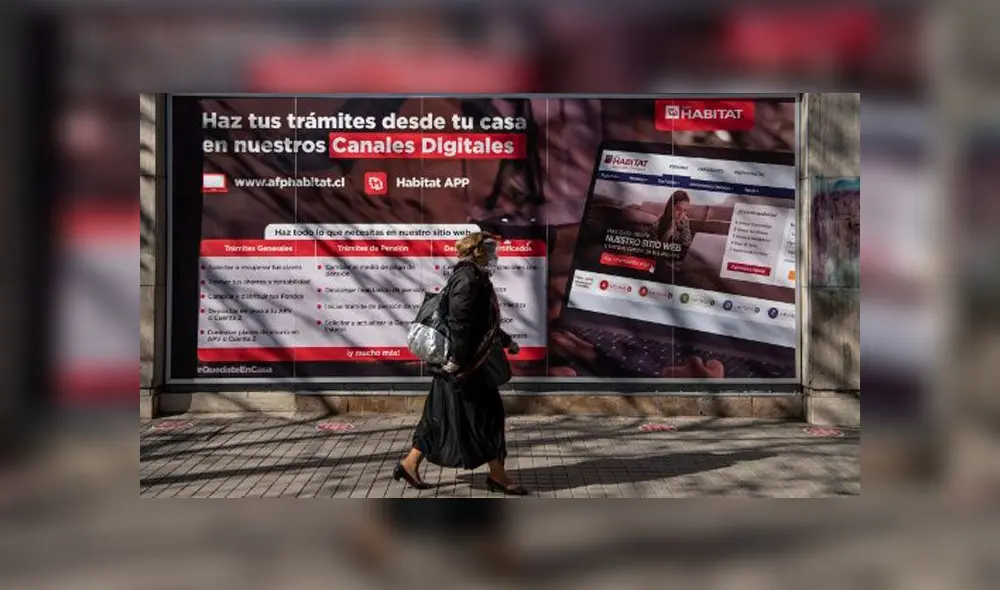 Una mujer pasa frente a una oficina de la Administración de Fondos de Pensiones (AFP) en Santiago. Foto: AFP.