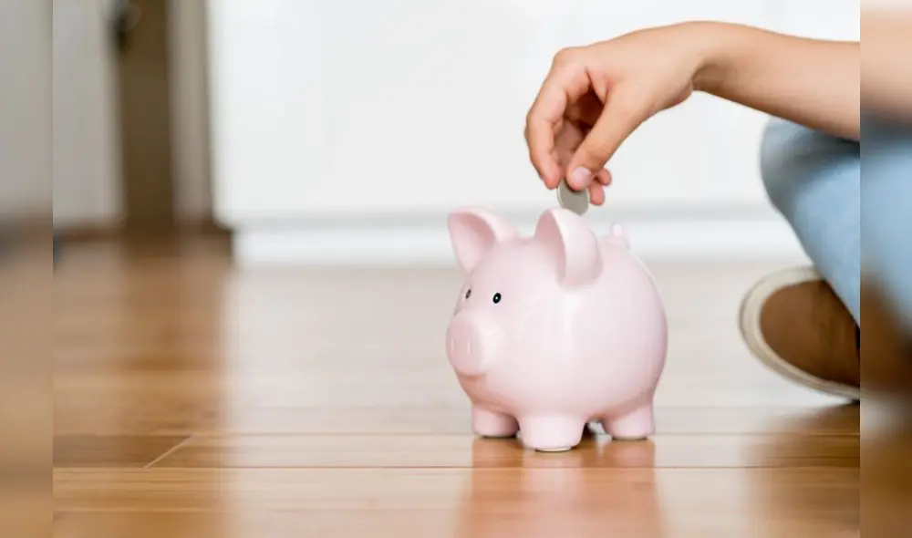 Close up of a boy saving money in a piggybank - home finances concepts