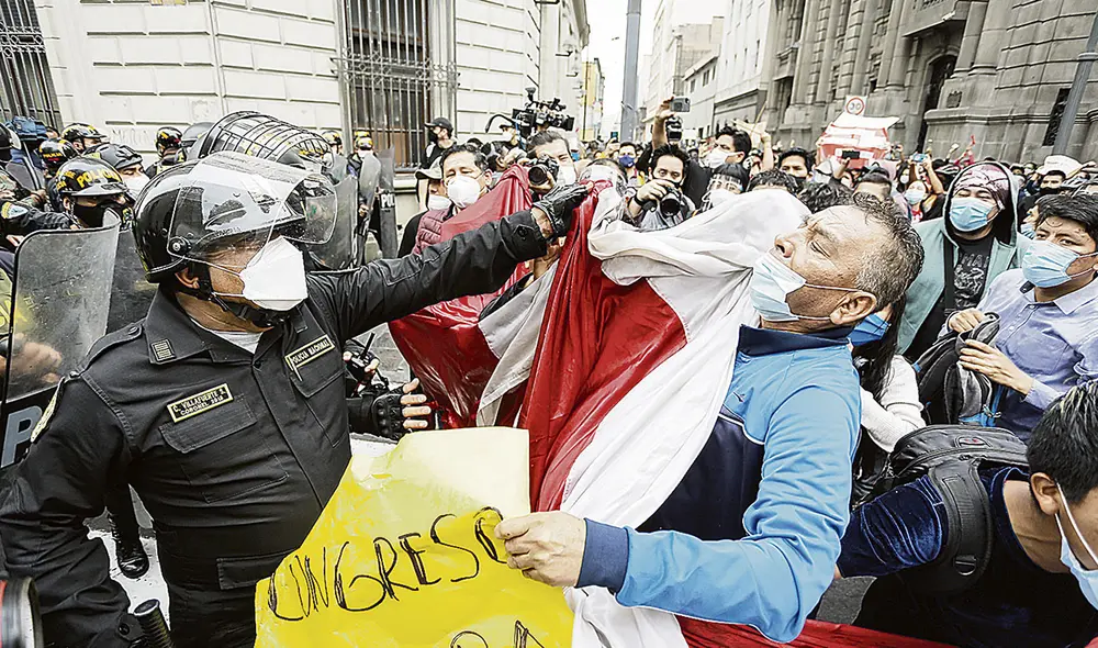 Afrenta. Un miembro de las fuerzas policiales es captado agrediendo a un manifestante que se negaba a que le quiten la bandera. Ocurrió en el jirón Carabaya el martes en la mañana. Pese a ello, el jefe de la PCM, Ántero Flores-Aráoz, y el ministro del Interior, Gastón Rodríguez, lo felicitaron. Foto: Antonio Melgarejo/La República Afrenta. Un miembro de las fuerzas policiales es captado agrediendo a un manifestante que se negaba a que le quiten la bandera. Ocurrió en el jirón Carabaya el martes en la mañana. Pese a ello, el jefe de la PCM, Ántero Flores-Aráoz, y el ministro del Interior, Gastón Rodríguez, lo felicitaron. Foto: Antonio Melgarejo/La República