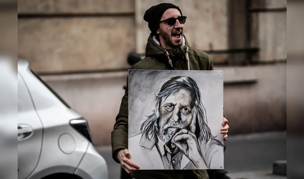 A man holding a painting of French infectious diseases specialist Didier Raoult dances at 20:00 along with others across the French nation, to show their support to healthcare employees in Saint-Mande, a Paris' suburb, on May 11, 2020, on the first day of France's easing of lockdown measures in place for 55 days to curb the spread of the COVID-19 pandemic, caused by the novel coronavirus. (Photo by Martin BUREAU / AFP)