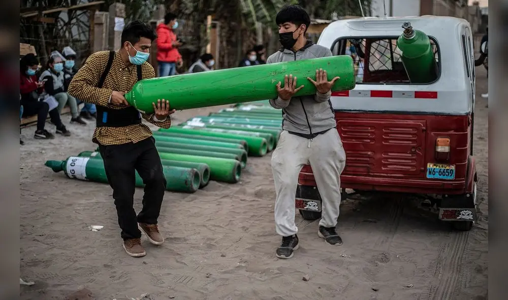 Dos hombres cargan un tanque de oxígeno vacío cuando llegan a la cola para recargarlo en Villa El Salvador, sur de Lima. Foto: Ernesto Benavides/AFP Dos hombres cargan un tanque de oxígeno vacío cuando llegan a la cola para recargarlo en Villa El Salvador, sur de Lima. Foto: Ernesto Benavides/AFP