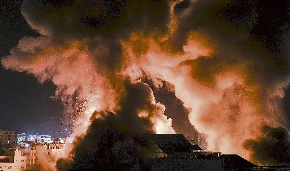 Conflicto. Las explosiones hacen iluminar el cielo nocturno sobre los edificios de Gaza. Foto: AFP Conflicto. Las explosiones hacen iluminar el cielo nocturno sobre los edificios de Gaza. Foto: AFP