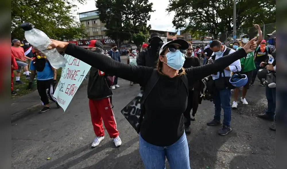 Manifestantes en Cali (Colombia) gritan consignas a policías durante una nueva protesta contra el Gobierno de Duque. Foto: AFP
