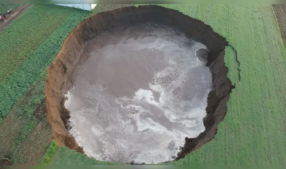 El socavón está relleno de agua, rodeado por campos verdes y acordonado por las autoridades. Foto: captura de Twitter/@PC_Estatal