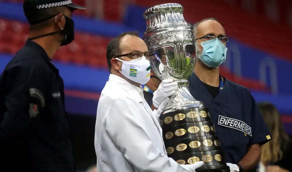 Trabajadores sanitarios cargan la Copa América previo al partido inaugural en el estadio Mané Garrincha de Brasilia. Foto: EFE/ Fernando Bizerra