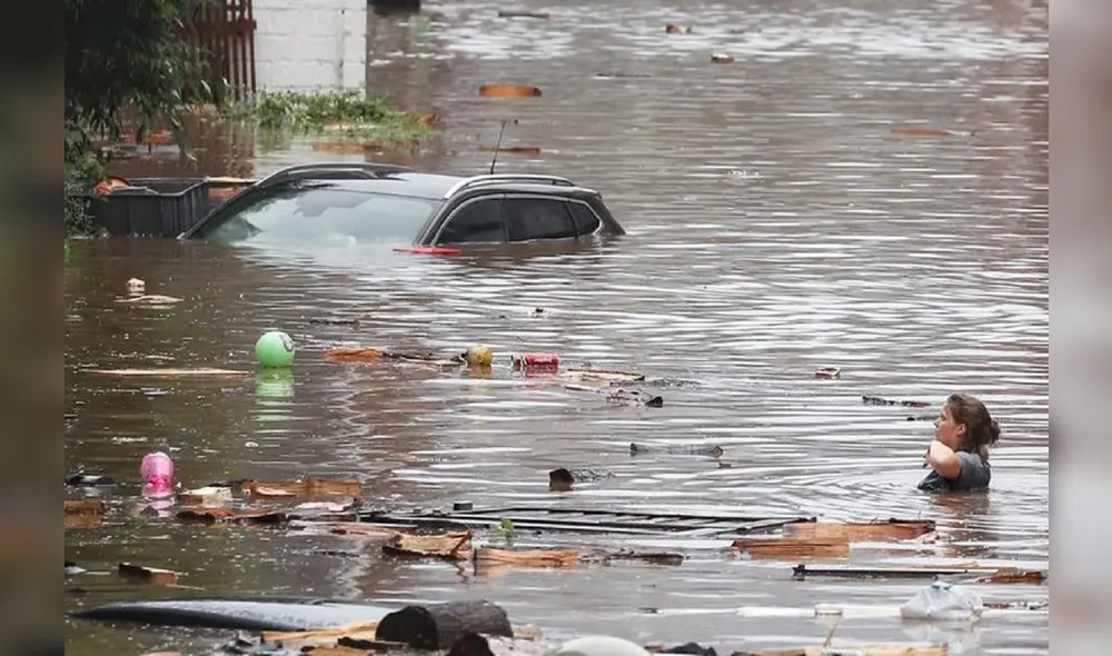 Una mujer trata de cruzar la calle con el agua al cuello en Lieja, Bélgica. Foto: AFP Una mujer trata de cruzar la calle con el agua al cuello en Lieja, Bélgica. Foto: AFP