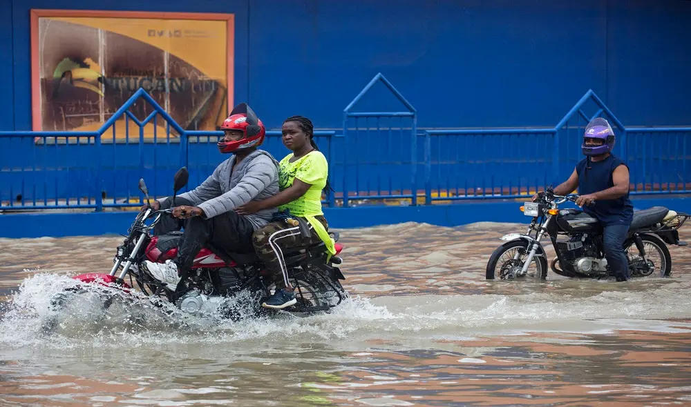 Personas se movilizan en motocicleta por una calle inundada luego del paso de la tormenta tropical Grace en Santo Domingo, República Dominicana. Foto: AFP