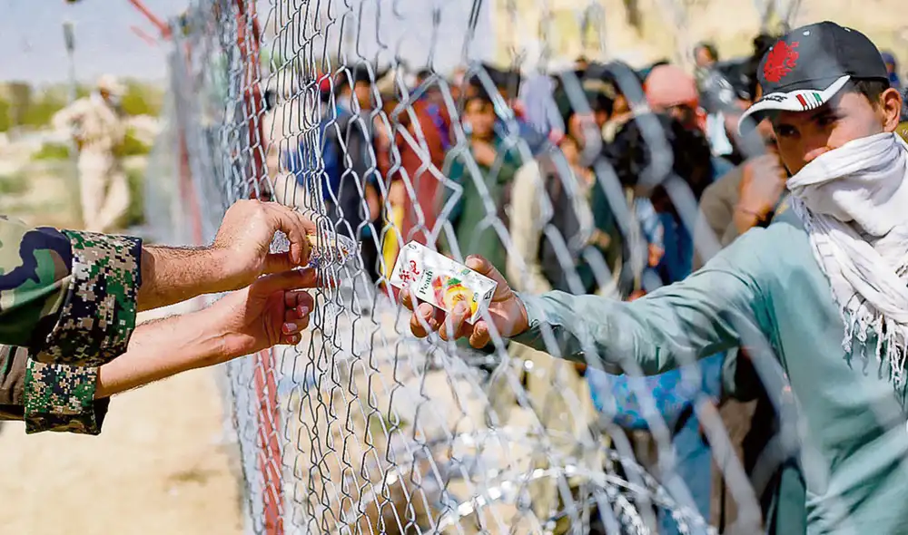 Salida. Un soldado iraní distribuye cajas de jugo a los refugiados afganos reunidos en la frontera entre Irán y Afganistán. Foto: difusión Salida. Un soldado iraní distribuye cajas de jugo a los refugiados afganos reunidos en la frontera entre Irán y Afganistán. Foto: difusión