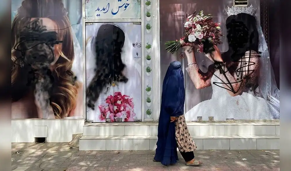 Una afgana vestida con burka pasa cerca de los carteles de un centro de belleza, en Kabul. Foto: Agencia Anadolu