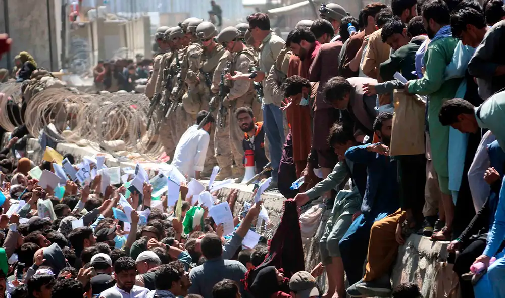 Numerosos afganos en las afueras del aeopuerto de Kabul muestran credenciales mientras intentan contactar con las fuerzas internacionales para intentar huir del país. Foto. EFE