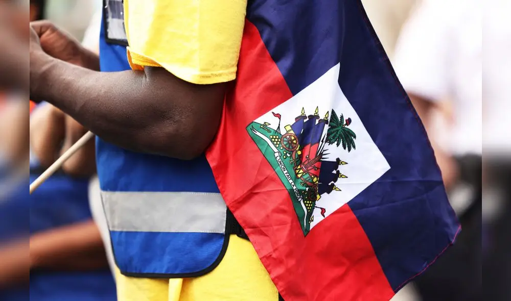 Un hombre sostiene una bandera haitiana durante una vigilia de fe. Foto: Michael M. Santiago/AFP/referencial Un hombre sostiene una bandera haitiana durante una vigilia de fe. Foto: Michael M. Santiago/AFP/referencial