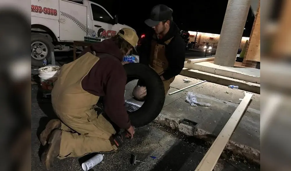 Los hermanos Heath (i) y Tristan (d) Hudson se afanan en mitad la noche del sábado y con una temperatura bajo cero en arreglar el neumático de una ambulancia en Mayfield, Kentucky.  Foto: EFE