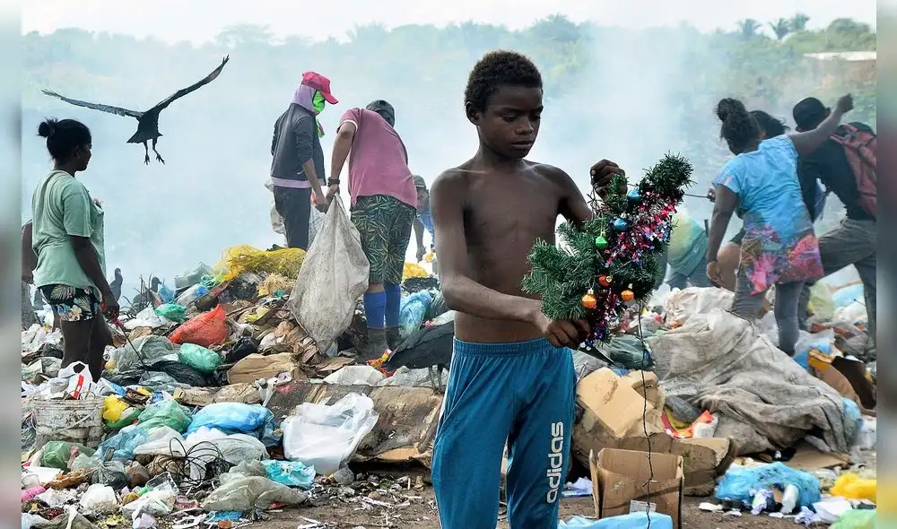 Gabriel sostiene una decoración navideña que encontró mientras hurgaba en la basura en el vertedero. Foto: AFP