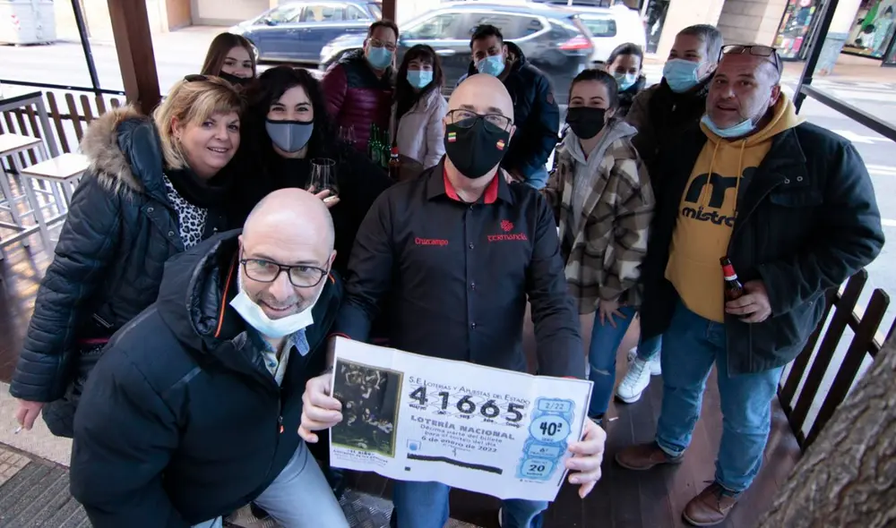 José Félix Aramayo sostiene una copia del número premiado entre algunos clientes y amigos. Foto: Gonzalo Monteseguro