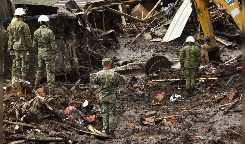Miembros del ejército observan una retroexcavadora que busca víctimas en medio del lodo en el barrio La Gasca, en Quito. Foto: AFP