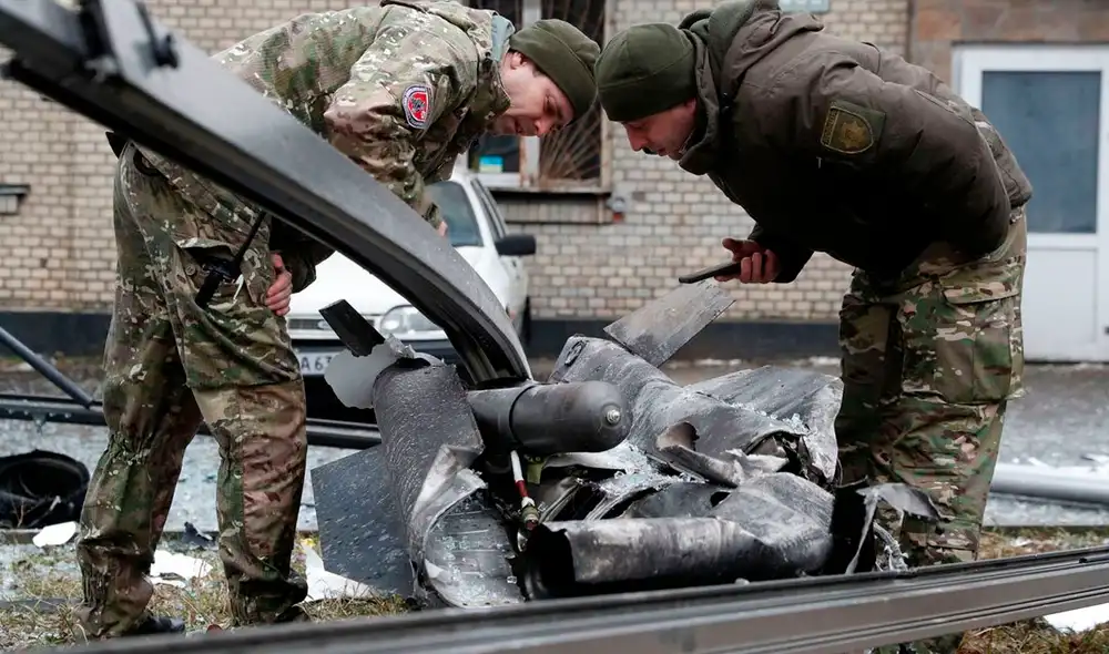 Un policía y personal de seguridad miran con atención los restos de un proyectil caído en Kiev, el 24 de febrero de 2022. Foto: AFP