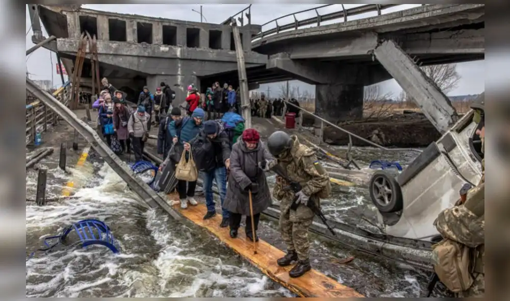 Civiles cruzan un puente destruido mientras huyen del asedio en la ciudad de Irpin, en Ucrania. Foto: EFE