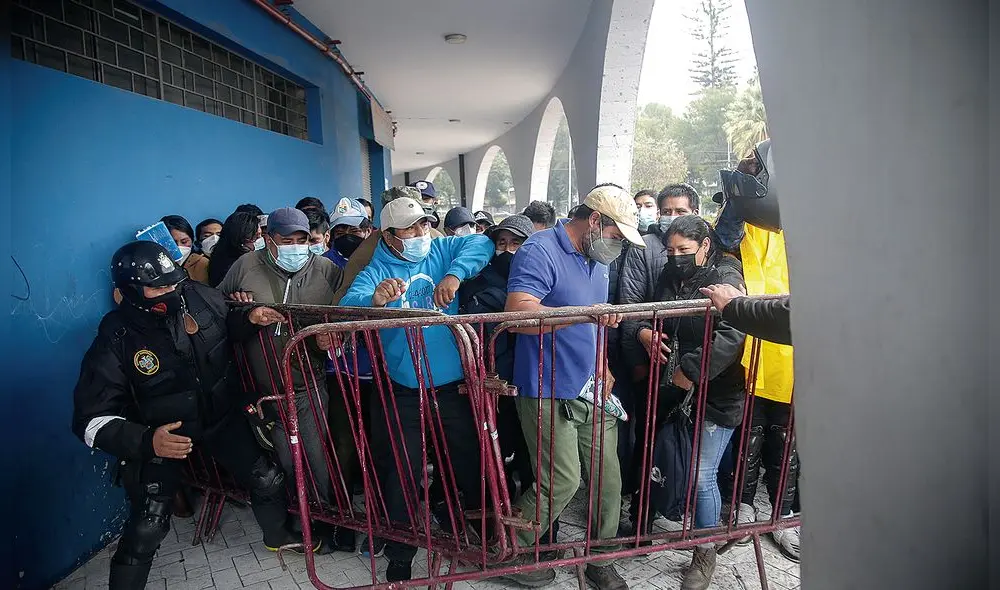 A la mala. Ciudadanos que compraron carpetas para remate y que no pudieron ingresar al coliseo Arequipa, intentaron traerse abajo vallas de ingreso. Personal municipal los retuvo. Foto: Rodrigo Talavera/ La República