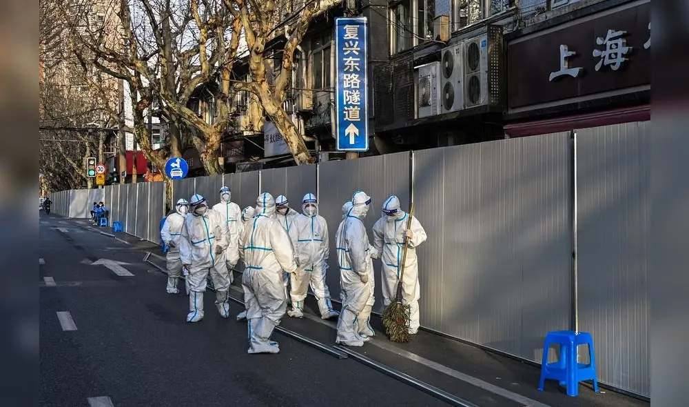 Los trabajadores laboran con ropa protectora en un área donde se están colocando barreras para cerrar las calles alrededor de algunas áreas de confinamiento. Foto: AFP Los trabajadores laboran con ropa protectora en un área donde se están colocando barreras para cerrar las calles alrededor de algunas áreas de confinamiento. Foto: AFP