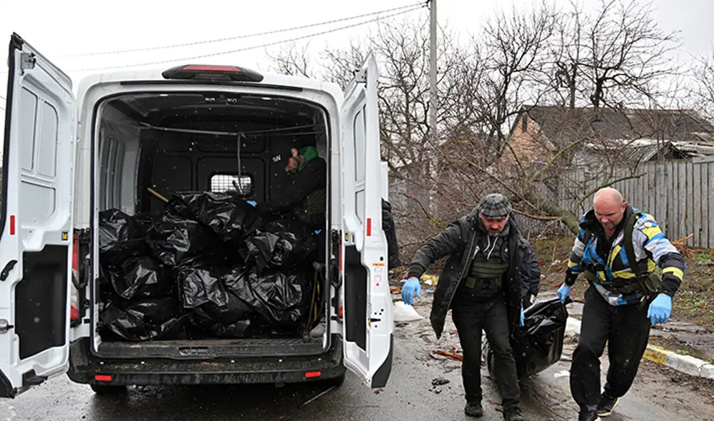 Trabajadores comunales llevan el cuerpo de un hombre civil asesinado por tropas rusas que bombardearon la ciudad de Bucha. Foto: AFP
