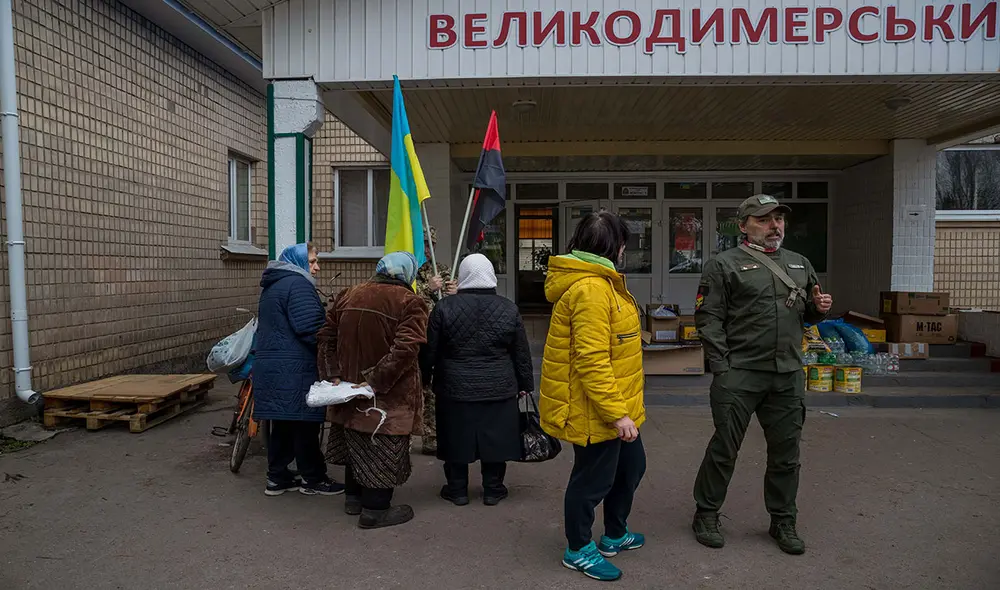 Chaparro (d) conversa con una mujer ucraniana mientras reparte comida en Rozhivka el 14 de abril. Foto: EFE
