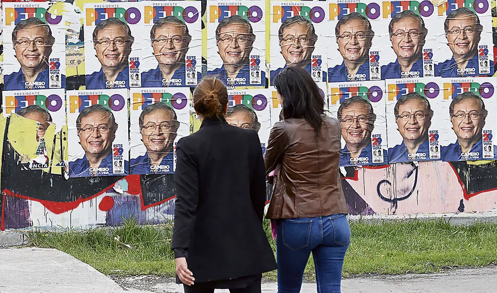 En campaña. Dos colombianas caminan cerca de volantes publicitarios del candidato presidencial Gustavo Petro, en Bogotá. Foto: EFE