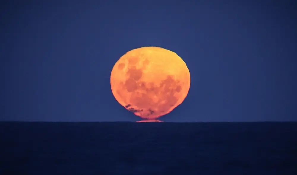 Fotografía de una luna llena en el horizonte. Foto: David Gray / AFP Fotografía de una luna llena en el horizonte. Foto: David Gray / AFP