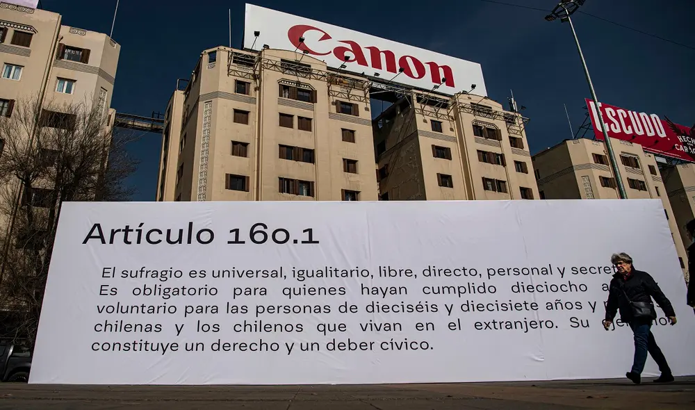 Una mujer camina frente a un cartel con un artículo de la nueva constitución para generar un debate callejero sobre la propuesta y llamar a votar el próximo 4 de septiembre. Foto: AFP