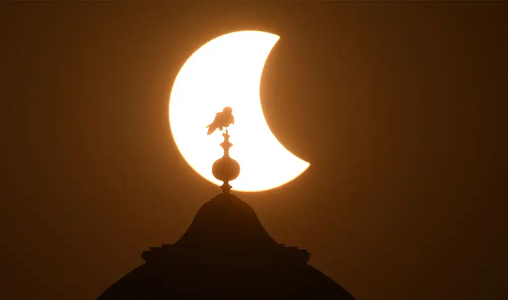 Un ave reposa sobre una cúpula durante el eclipse solar de hoy, 25 de octubre de 2022, en Lahore, Pakistán. Foto: AFP