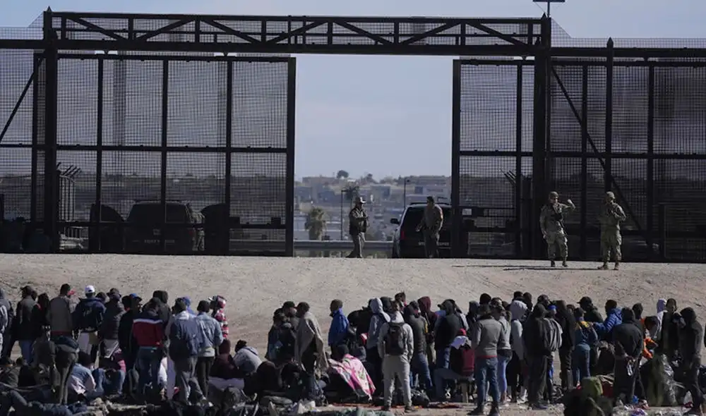 Migrantes que cruzaron la frontera de México hacia EE. UU. esperan junto al muro. Foto: AP Migrantes que cruzaron la frontera de México hacia EE. UU. esperan junto al muro. Foto: AP