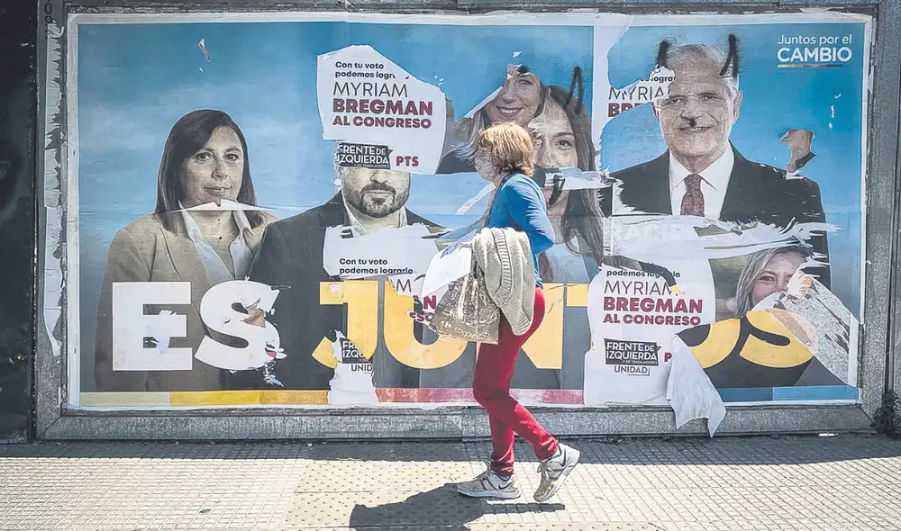 Saben y opinan. Una porteña camina frente un cartel vandalizado por los contrarios. La guerra sucia mandó en la campaña. Foto: EFE Saben y opinan. Una porteña camina frente un cartel vandalizado por los contrarios. La guerra sucia mandó en la campaña. Foto: EFE